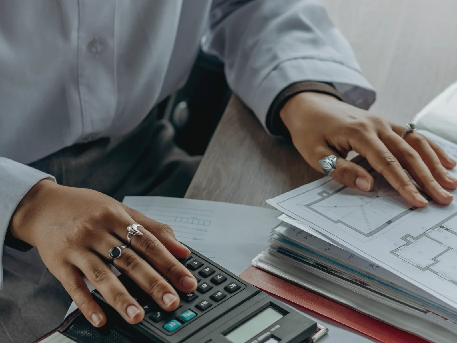 Hands reviewing organized paperwork beside a calculator