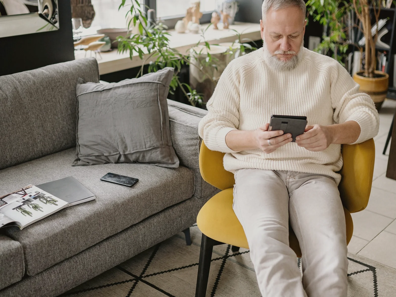 Older adult using a tablet while seated in a living room