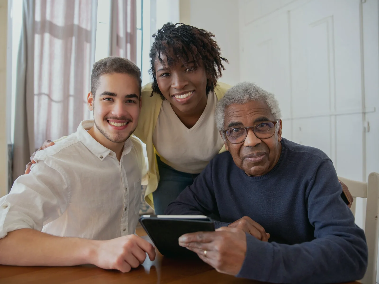 Older adult and two household members reviewing a tablet together
