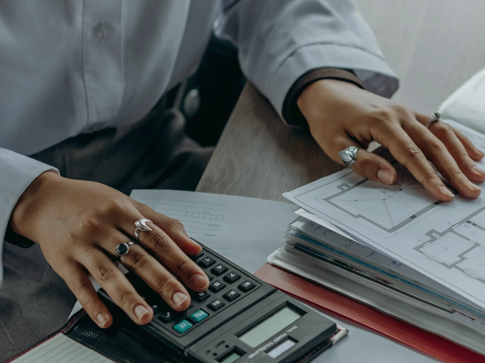 Hands reviewing a weekly plan and folders beside a calculator
